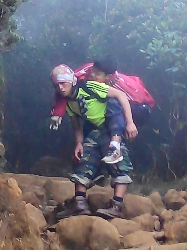 Mountain guide carrying a child to safety following the Sabah earthquake